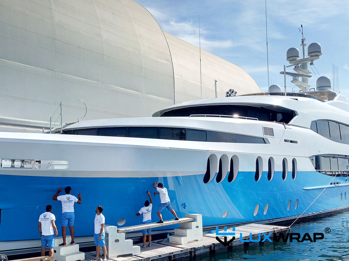 LuxWrap team admiring a completed 60-metre superyacht hull wrap, installed in the water