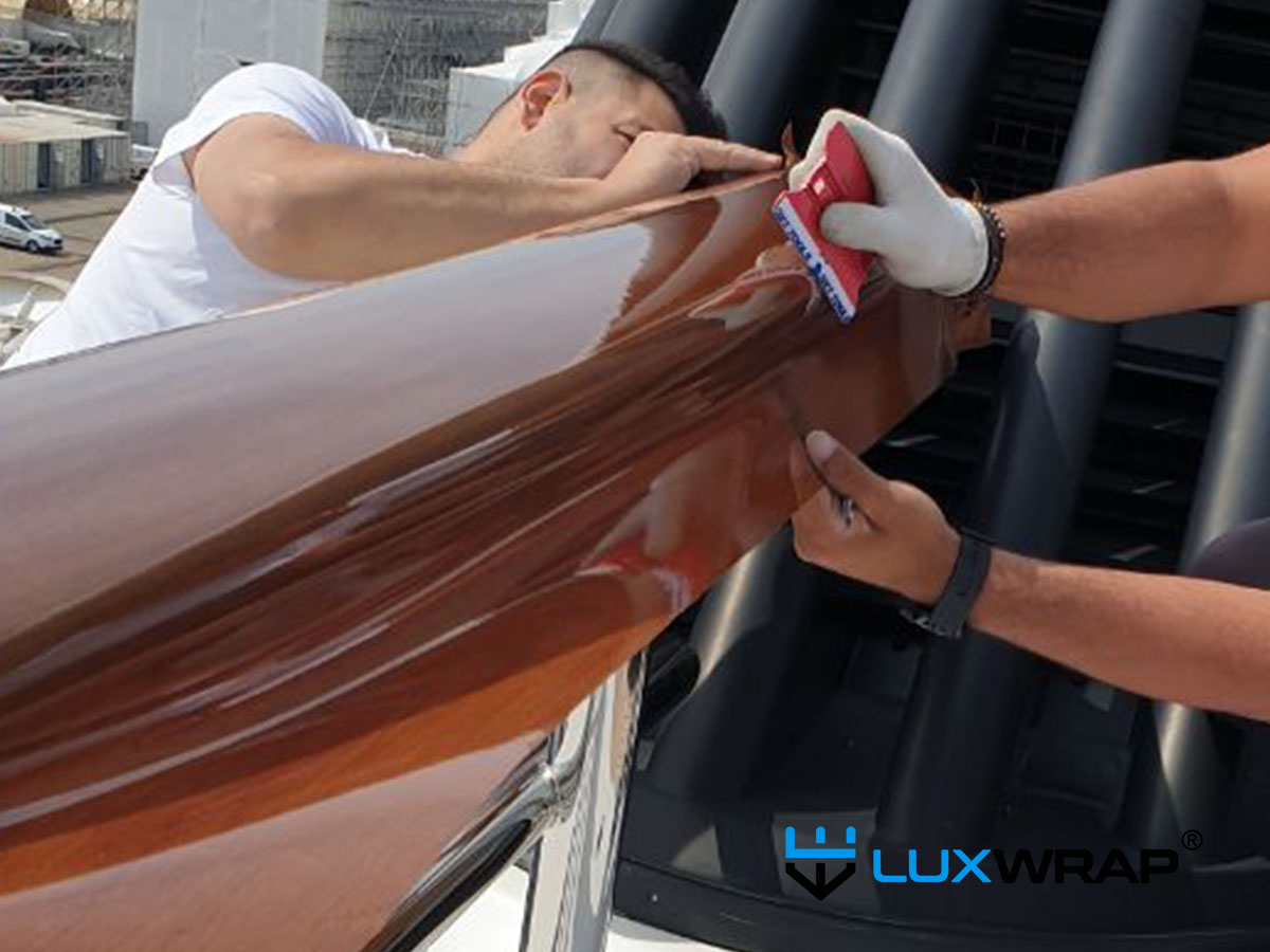 High-gloss wood grain architectural film protected with NinjaShield PPF applied to superyacht cap rails — matching existing varnished wood