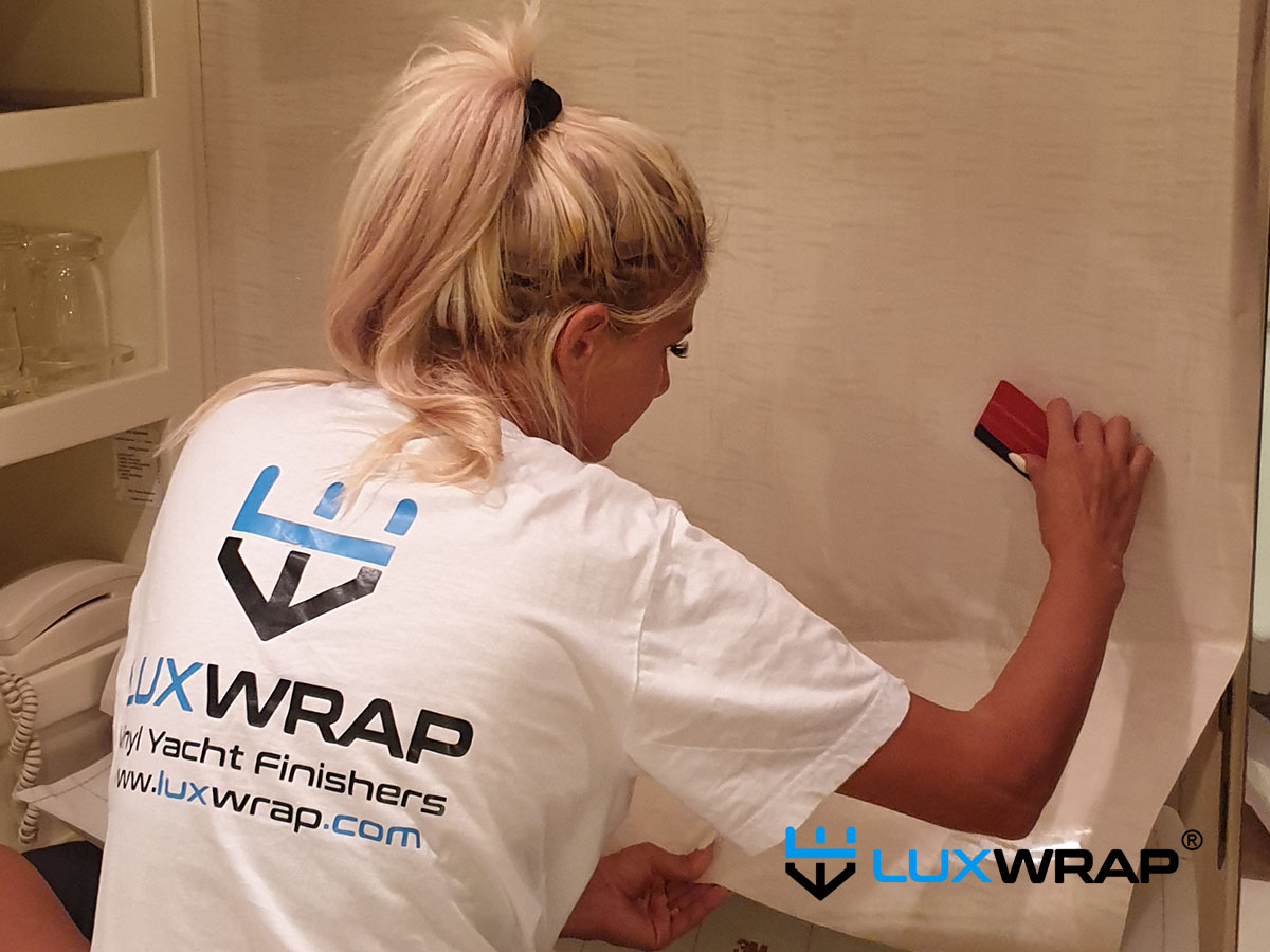LuxWrap installer applying architectural vinyl film to superyacht interior joinery