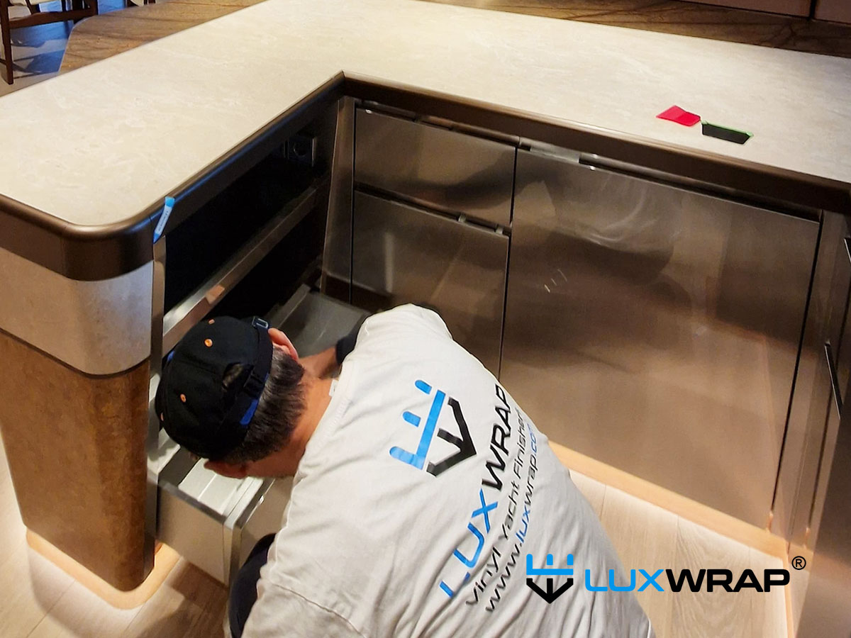 Superyacht galley base units wrapped with high-gloss PPF surface protection film during LuxWrap installation