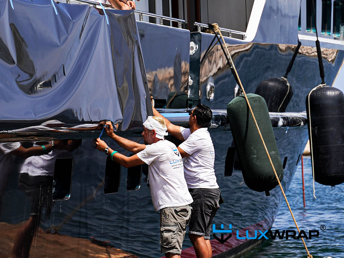 Superyacht being wrapped in the water from floating rafts by LuxWrap expert installers — chosen over painting for speed and cost