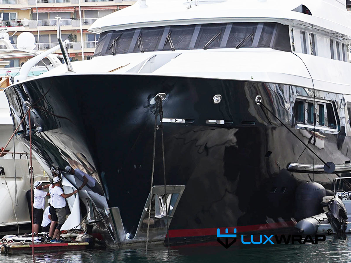 LuxWrap crew accessing a superyacht bow from a floating raft to wrap the hull