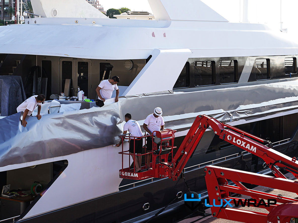 LuxWrap installers wrapping a large yacht superstructure using cherry pickers and step ladders