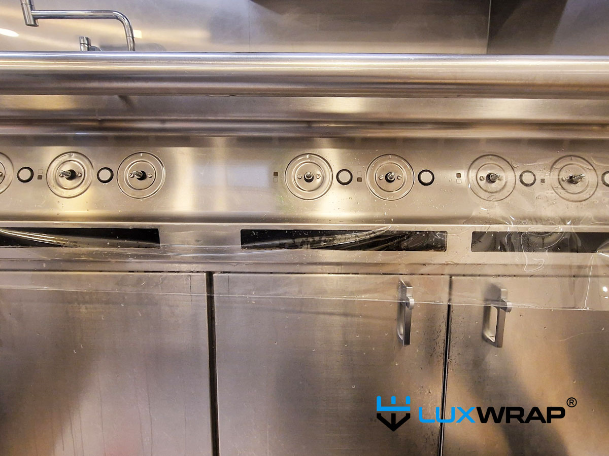 LuxWrap installation in progress — hob control area of an industrial galley cooker on a large superyacht, protected with surface protection film against scratches, abrasion, and daily operational wear.