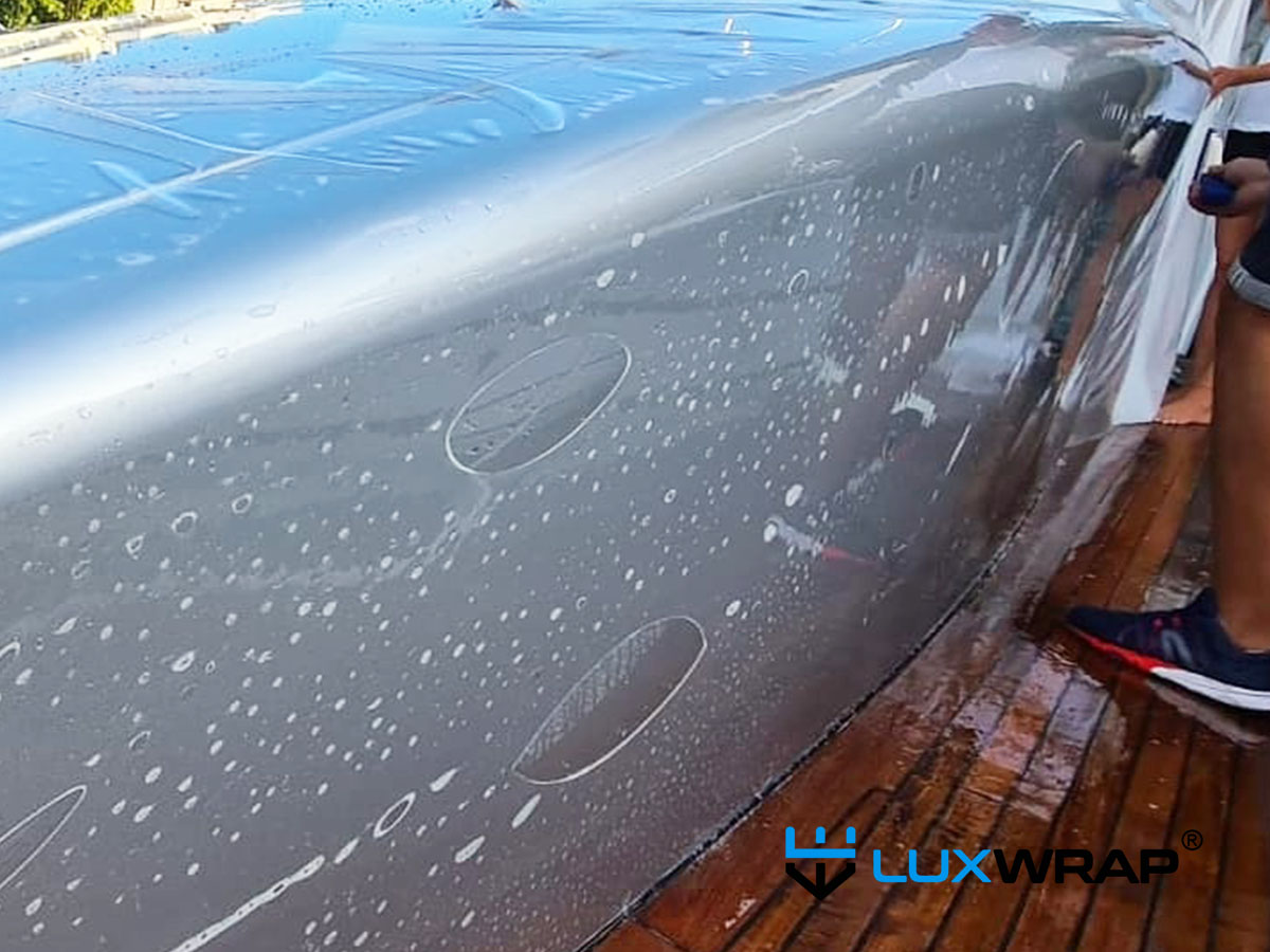 NinjaShield PPF wet installation on superyacht bulwark with slip solution and air pockets before squeegee finishing
